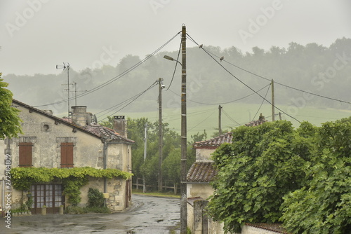 Colline verdoyante voilée par un filet d'eau lors d'une averse intense à Champagne au Périgord Vert