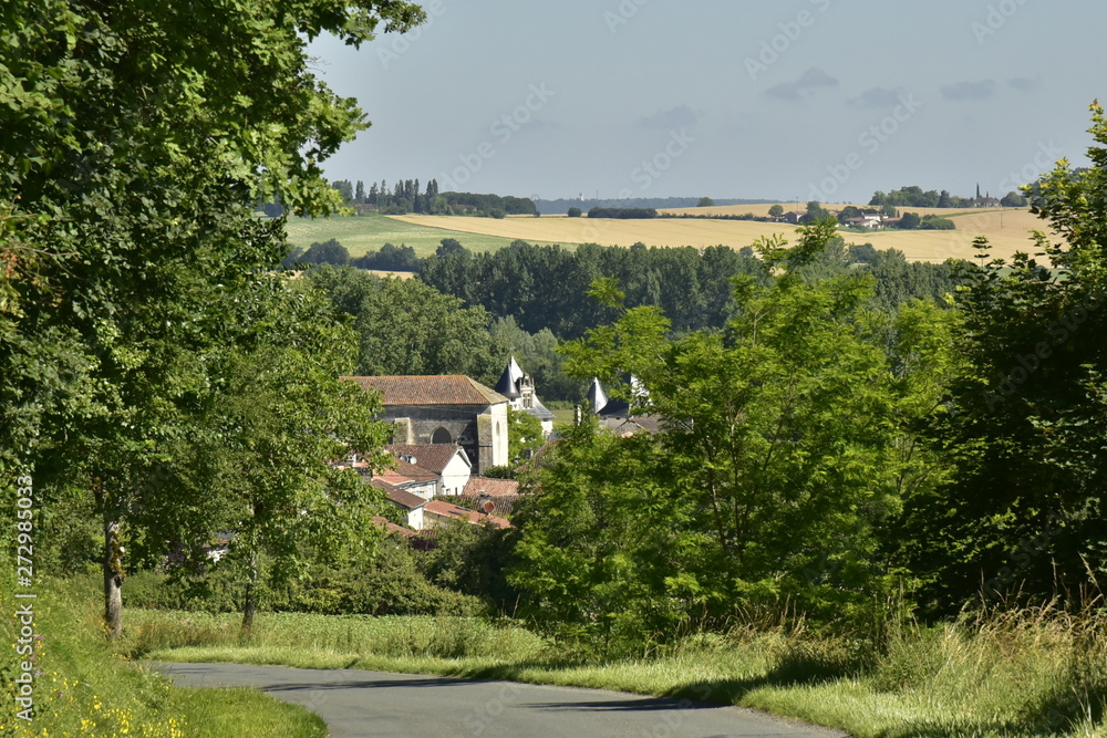 Route vers le village de Champagne avec son église romane et les tourelles du château émergeant des toits rustiques ,au Périgord Vert 