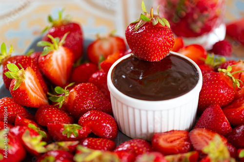Dipping of tasty strawberry into bowl with chocolate