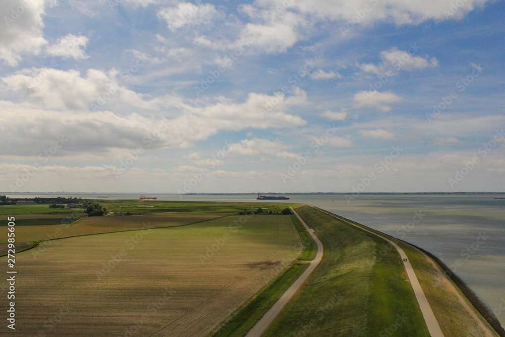 aerial view of the agricultural fields along the seawall of the westerschelde in holland in springtime and a blue sky with clouds 