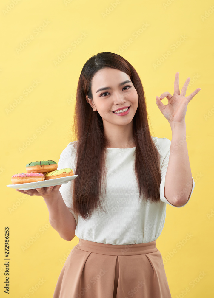 Beautiful young woman smiling holding a plate full of delicious color donuts Beautiful young woman smiling holding a plate full of delicious color donuts