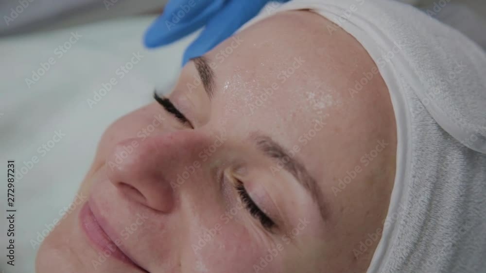 Professional cosmetologist applies the serum to the patient's face. Professional cosmetologist applies the serum to the patient's face.