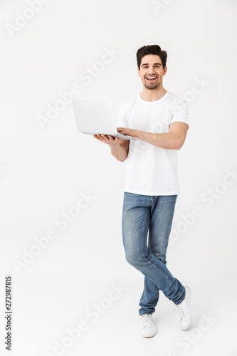 Excited young man posing isolated over white wall using laptop computer.