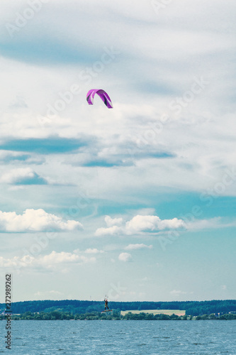 A kiteboarder is pulled across water by a power kite. Kitesurfer high in flight