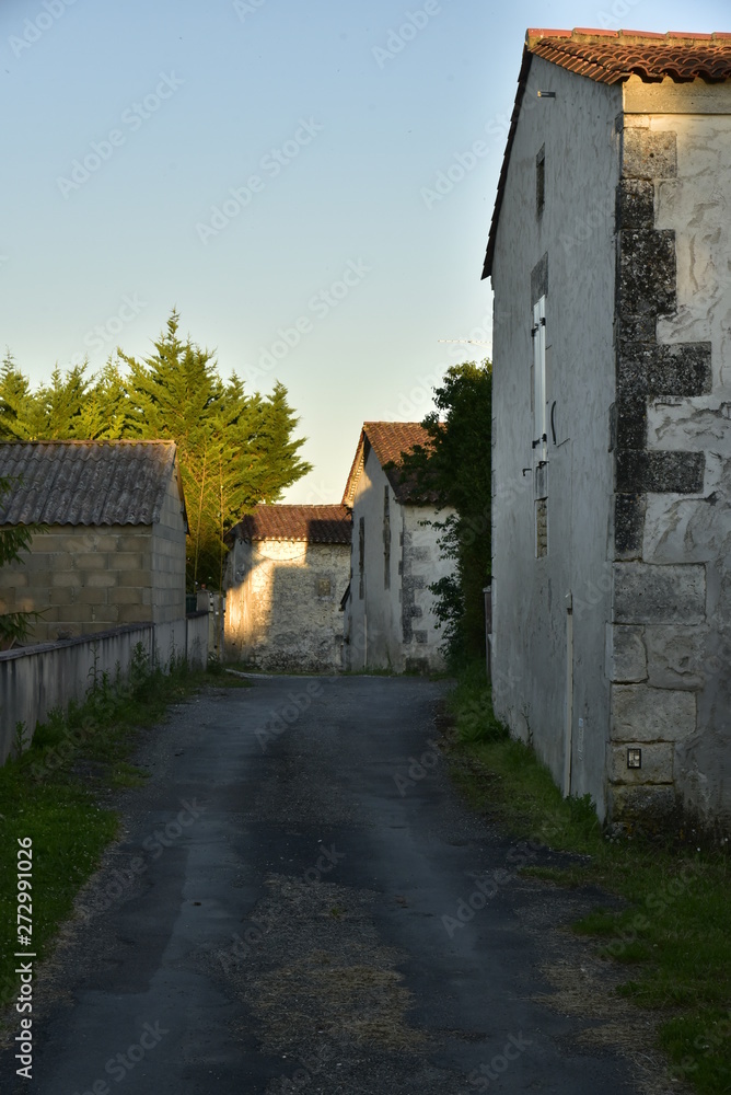 Route de campagne entre les vieux murs des fermes au coucher de soleil au Puy de Versac au Périgord Vert