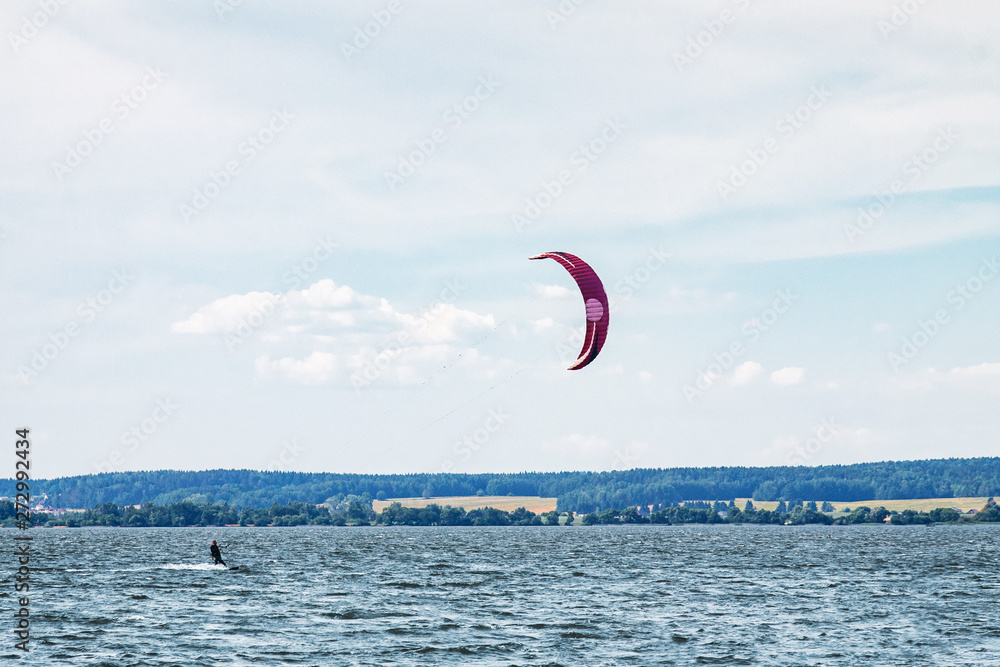 A kiteboarder is pulled across water by a power kite
