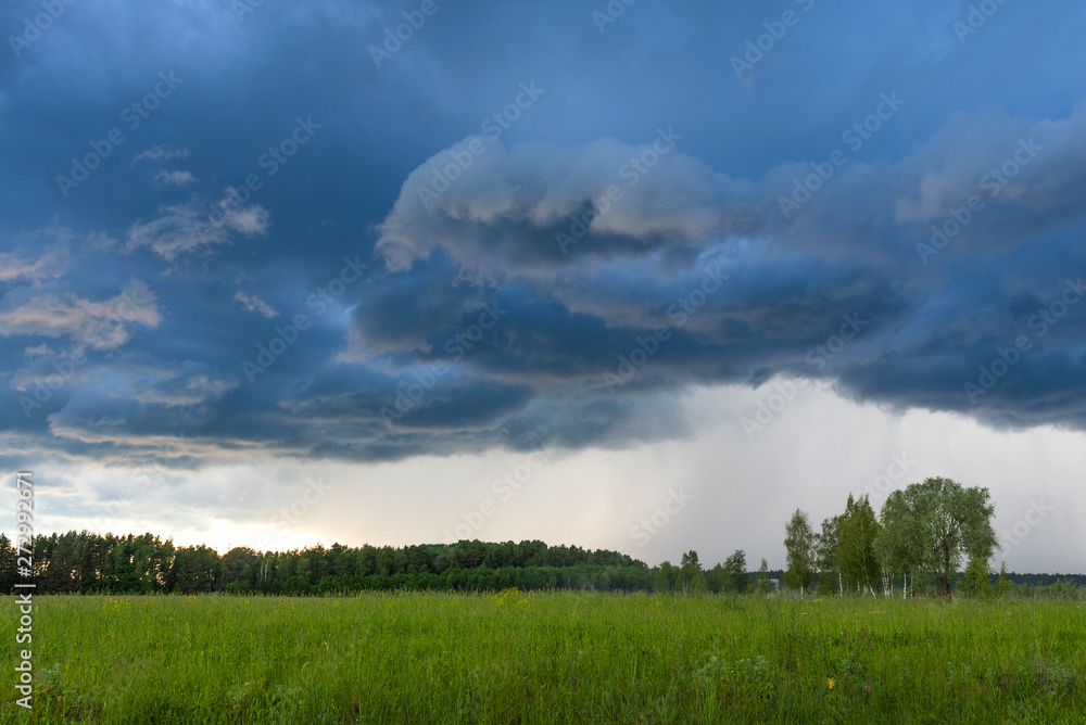Rural landscape green field with dramatic sky. Grey dark sky before thunderstorm in summer. Rural landscape green field with dramatic sky. Grey dark sky before thunderstorm in summer.