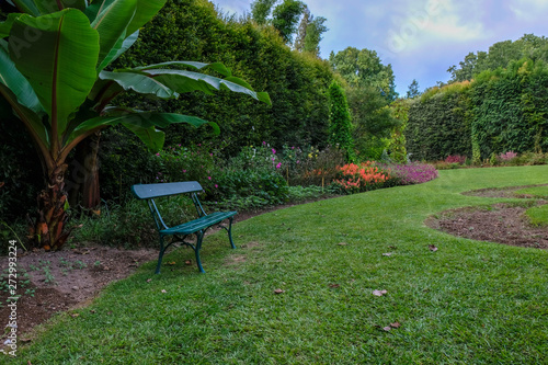 Garden green bench in the middle of a luxurious and beautiful garden in Furnas, São Miguel Island in the Azores