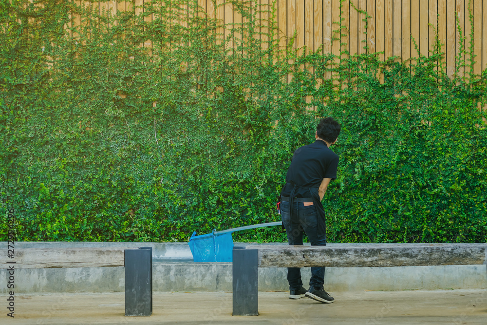 Fototapeta premium Young man cleaning fountain pool from fallen leaves with net .