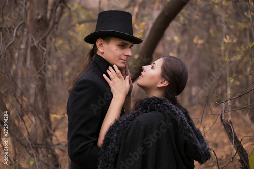 A woman and a man in nineteenth-century clothes in a gloomy forest. Man hugging a woman close up