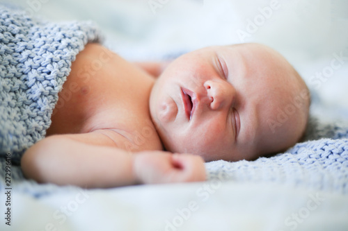 Newborn baby boy sleeping in children's cot - closeup