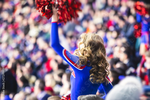 Photography Female cheerleader in red blue uniform with pom-pom with audience in the backgro