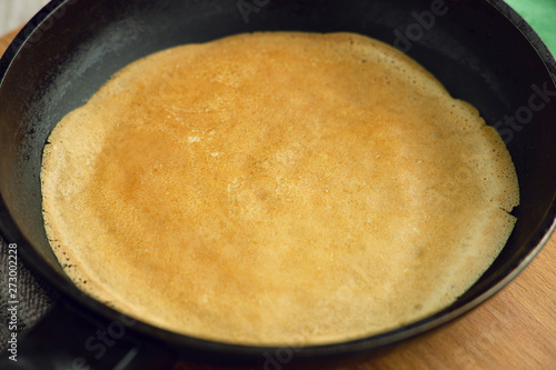 Thin pancake is fried in a pan. Pancake week. The process of cooking pancakes in a pan. Fry thin pancakes from dough close up.