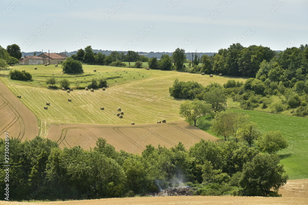 Meules fe foins faisant minuscules sur un champs sur une pente de colline dégagée au Périgord Vert