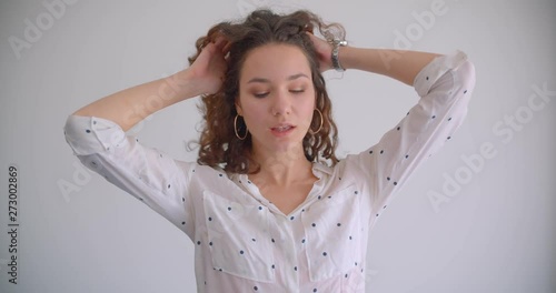 Closeup shoot of young stylish long haired curly caucasian female tossing hair seductively looking at camera with background isolated on white photo