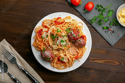 Delicious spaghetti pasta with meatballs and tomato sauce on a plate. Traditional American Italian food on a rustic wooden table. Top view shot directly above. © Maxim Khytra