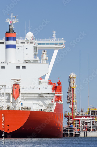 LNG TERMINAL AND GAS CARRIER - A large red ship moored to the wharf
