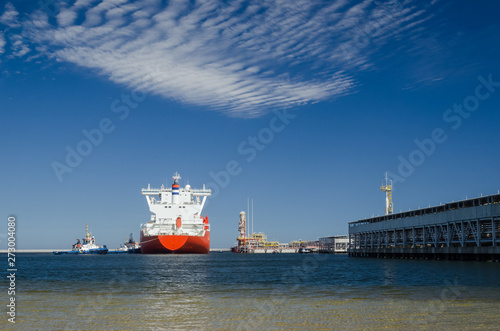 GAS TANKER AND LNG TERMINAL - The big ship maneuvers in the mooring port at the wharf