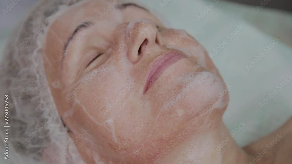 An elderly woman is lying on a couch in a cosmetology clinic. An elderly woman is lying on a couch in a cosmetology clinic.