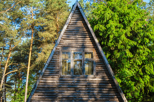 Fototapeta Naklejka Na Ścianę i Meble -  Wooden triangular roof with a large window in the cottage in the forest recreation area in the summer in Ukraine.