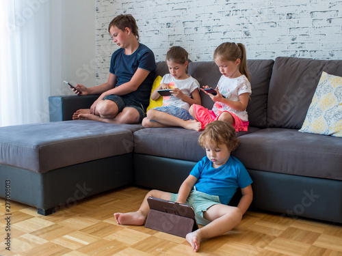 Obraz na płótnie young children use electronic gadgets, the concept of children's addiction of phones and tablets w salonie