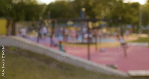 Blurred, out of focus shot of kids swinging on the playground. City life background, lens flare, Slow motion