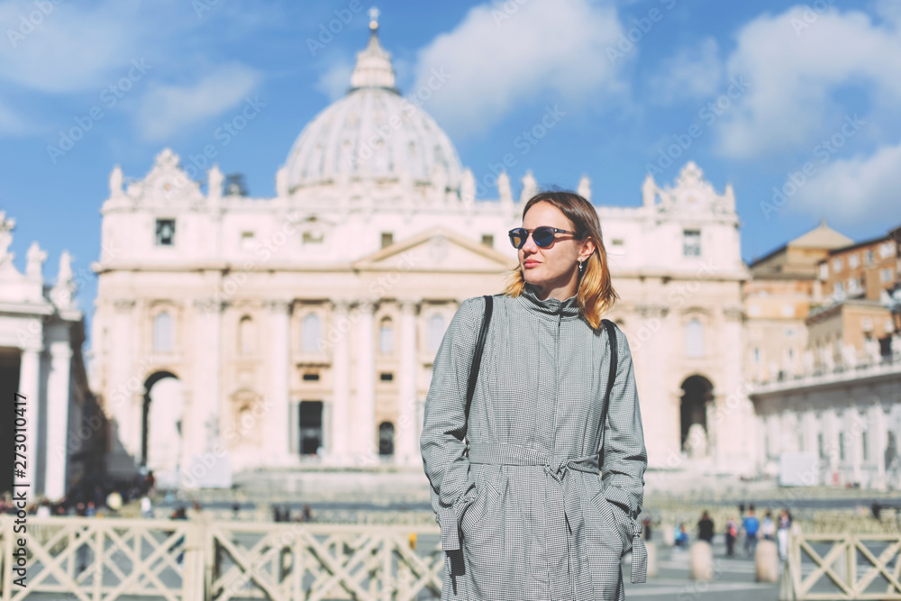 Stylish woman tourist in the Vatican, background with the image of the main Catholic cathedral.