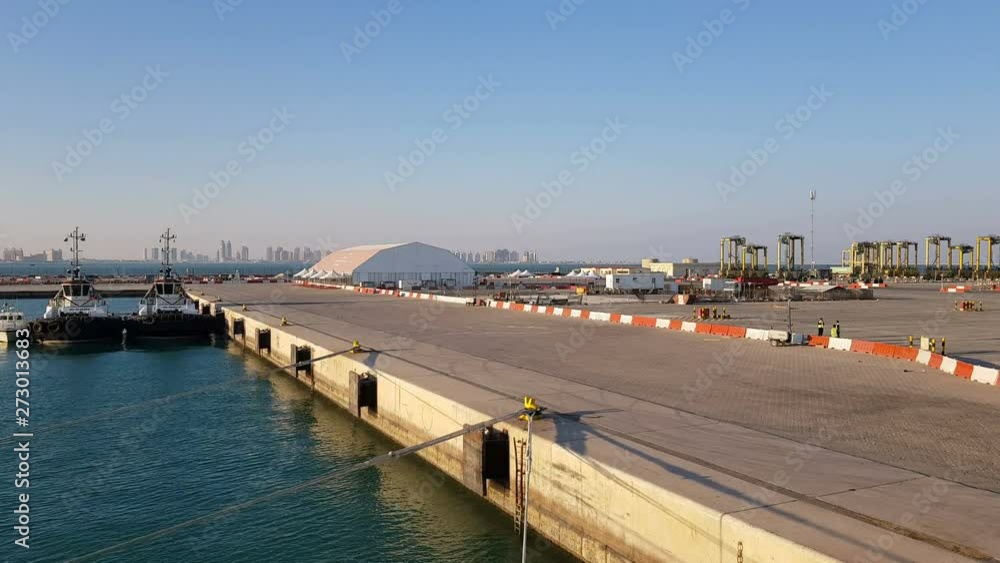 View of the pier with moored ships. Cargo seaport. Workers work in the cargo seaport. The mooring ropes on the pier. View of the pier with moored ships. Cargo seaport. Workers work in the cargo seaport. The mooring ropes on the pier.