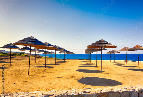 Sand beach with rows of strawy beach umbrellas