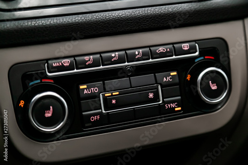 Сlose-up of the car black interior: seat heatting buttons, adjustment of the blower, air conditioner and other buttons.