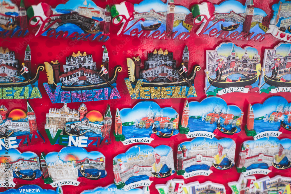 View of traditional tourist souvenirs and gifts from Venice, Italy and with toys, masquerade venetian masks, fridge magnets with text 