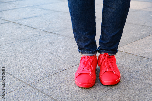 Date with . Girl's feet in shoes. Red sneakers and jeans. Waiting for a date.
