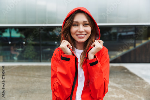 Beautiful excited emotional young happy pretty woman in raincoat posing outdoors.
