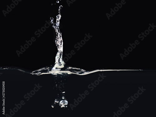 Splash on water surface isolated on black background, close up view. Drop falling into liquid. Bubbles underwater. Ready to use blending mode to screen or add