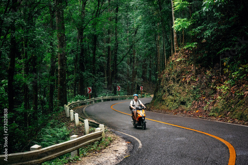 Canvas Print Man with backpack sits on road through green Bilar Man-Made Forest, Bohol, Phili