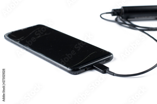 Black mobile phone and charger isolated on white background.Copy space
