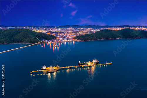 shipping oil and port dot loading oil and petrochemical in the sea and refinery factory zone with blue sky background at night