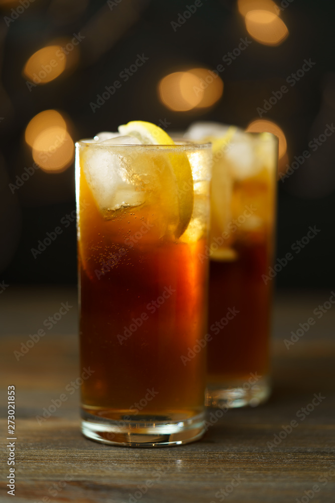 Rum and coke in a highball glass with a lemon wedge. Dark wooden table, festive lights, high resolution Rum and coke in a highball glass with a lemon wedge. Dark wooden table, festive lights, high resolution