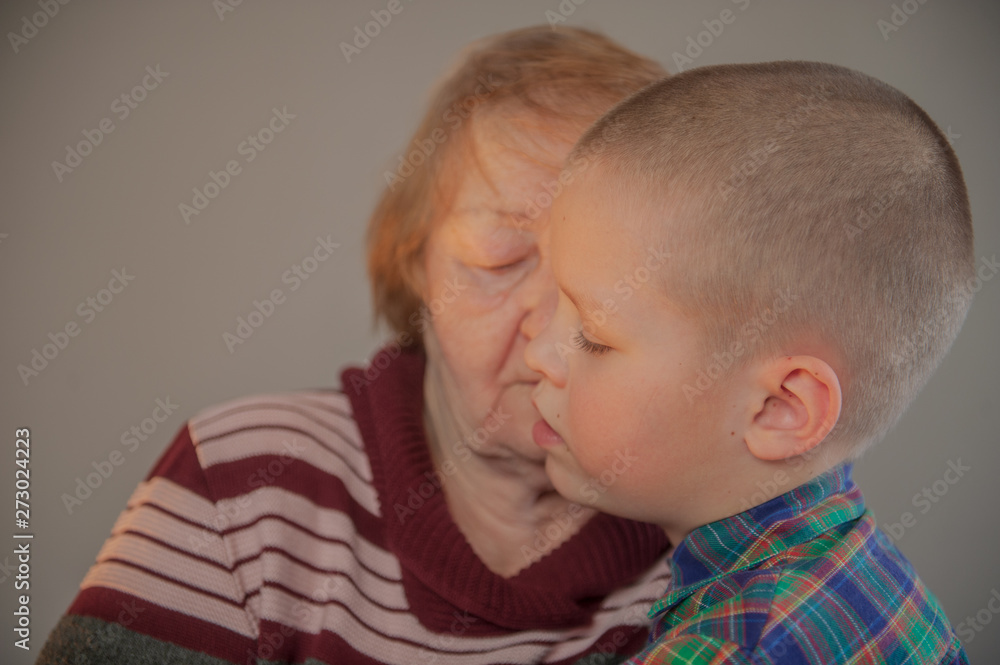 Elderly grandmother and grandson spend time together in green checkered shirt. Boy and the old woman are very attached to each other. Elderly grandmother and grandson spend time together in green checkered shirt. Boy and the old woman are very attached to each other.