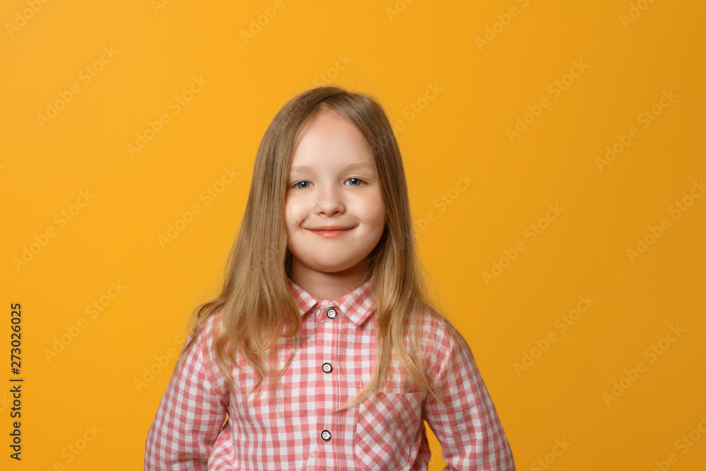 Closeup portrait of a funny little blond girl on yellow background. A child in a pink shirt is looking into the camera. Closeup portrait of a funny little blond girl on yellow background. A child in a pink shirt is looking into the camera.