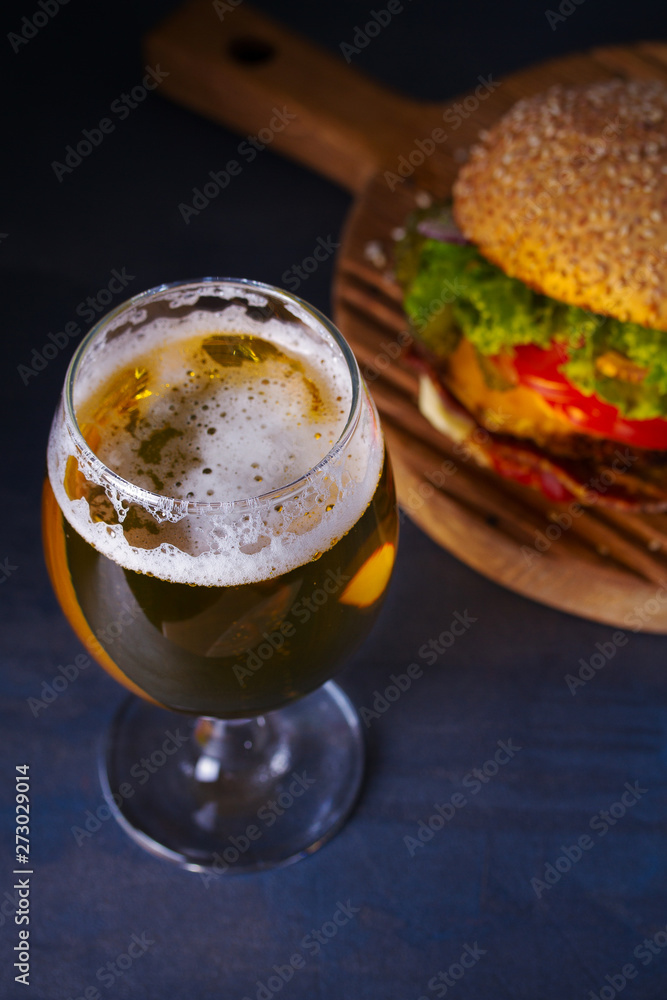 Beer and burger on wooden board for serving. Beer and food concept - Image Beer and burger on wooden board for serving. Beer and food concept - Image