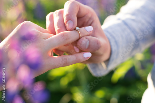 The young guy puts the ring on the finger of his beloved girlfriend. Wedding, marriage, love, union, family. © miztanya