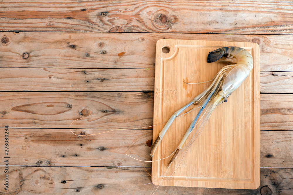 Big prawns on the wooden chopping board on the wooden table Big prawns on the wooden chopping board on the wooden table