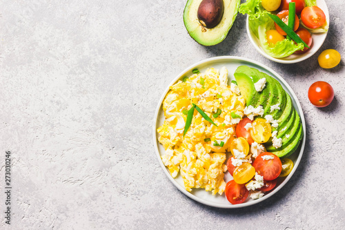 Scrambled eggs with cherry tomatoes , avocado feta cheese and olive oil. Top view, space for text.