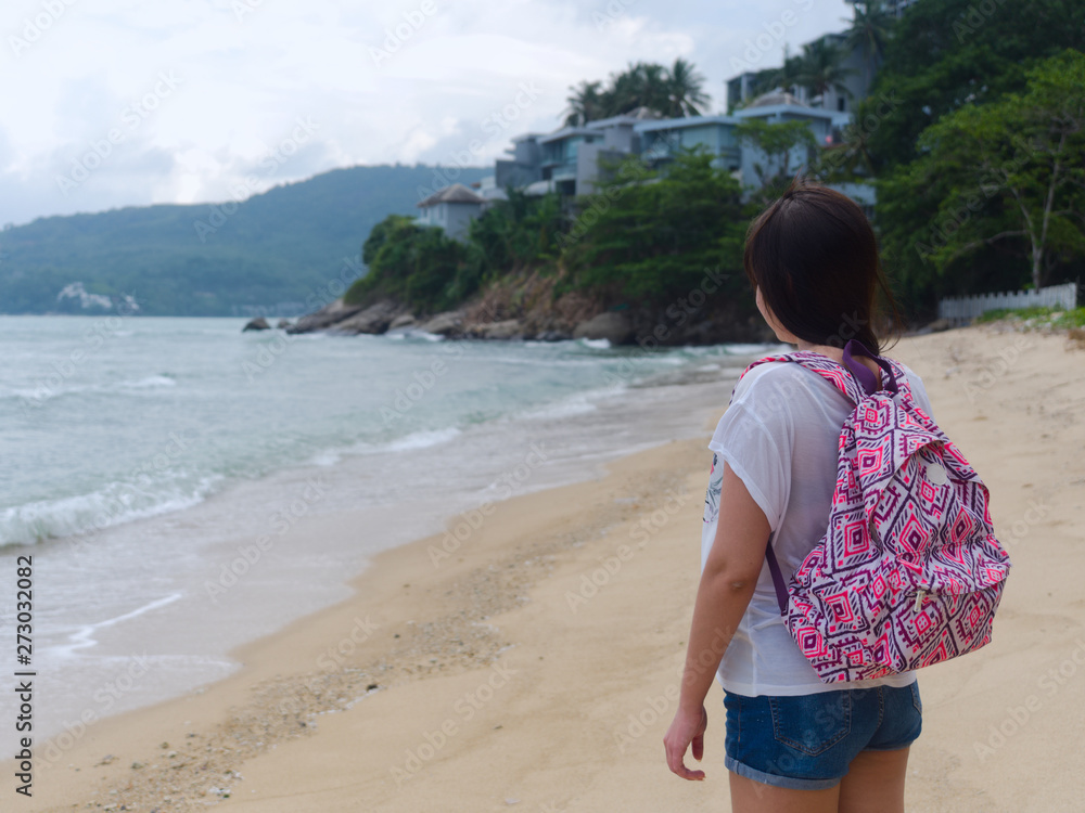 young traveler girl with a backpack, standing on an empty beach and enjoys the scenery young traveler girl with a backpack, standing on an empty beach and enjoys the scenery