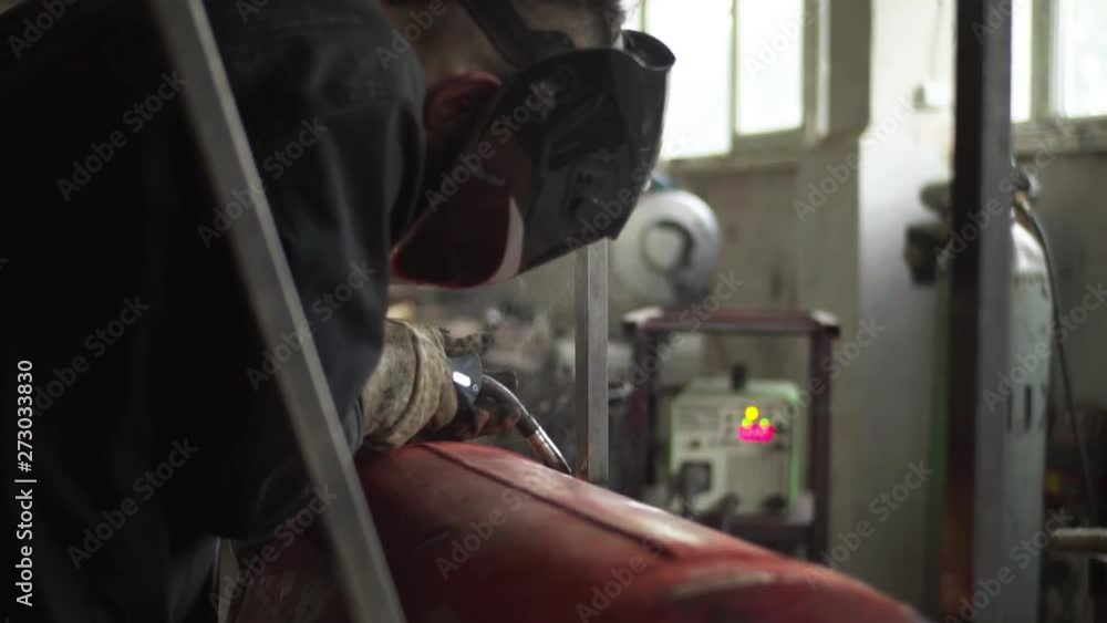 Workers in the mask are welding steel in workshop Workers in the mask are welding steel in workshop