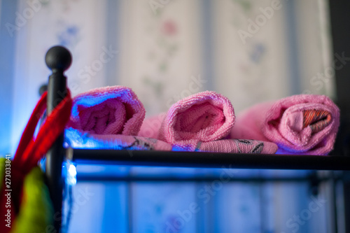 три розовых полотенца скрученных в трубочки лежат на черной полке.JPG