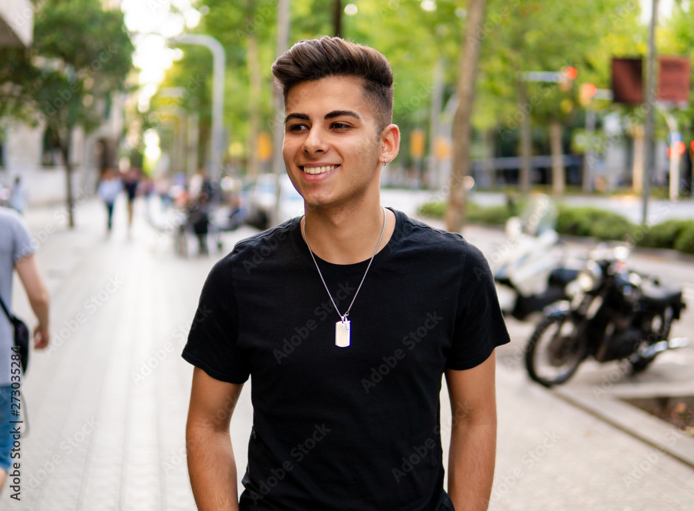 Young fashionable handsome man on the street of modern city. He looks happy Young fashionable handsome man on the street of modern city. He looks happy