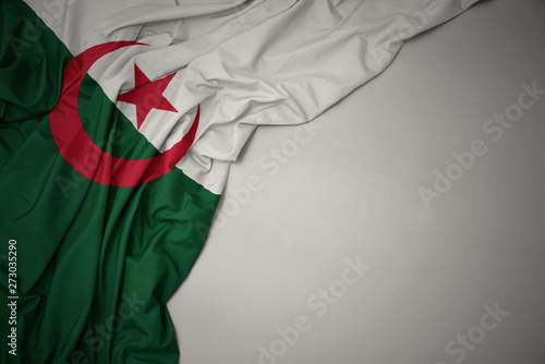 waving national flag of algeria on a gray background.