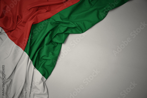 waving national flag of madagascar on a gray background.
